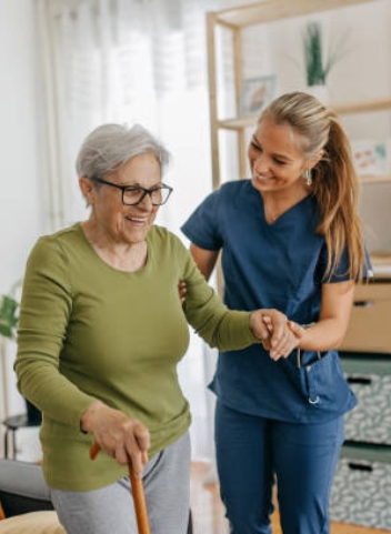 A caregiver helping a resident walk with a cane